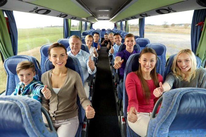 Un groupe de voyageurs heureux fait le signe du pouce levé à l'intérieur d'un bus, profitant pleinement de leur voyage de groupe organisé.