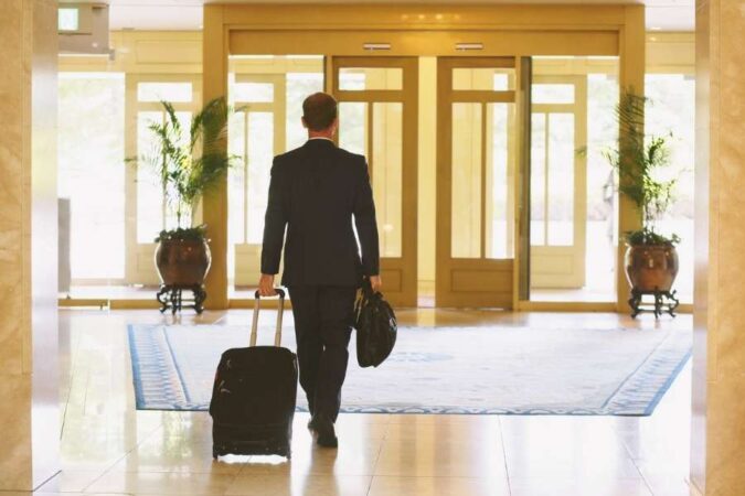 Un homme en costume tire sa valise dans le hall d'un établissement lors de son voyage d'affaires.
